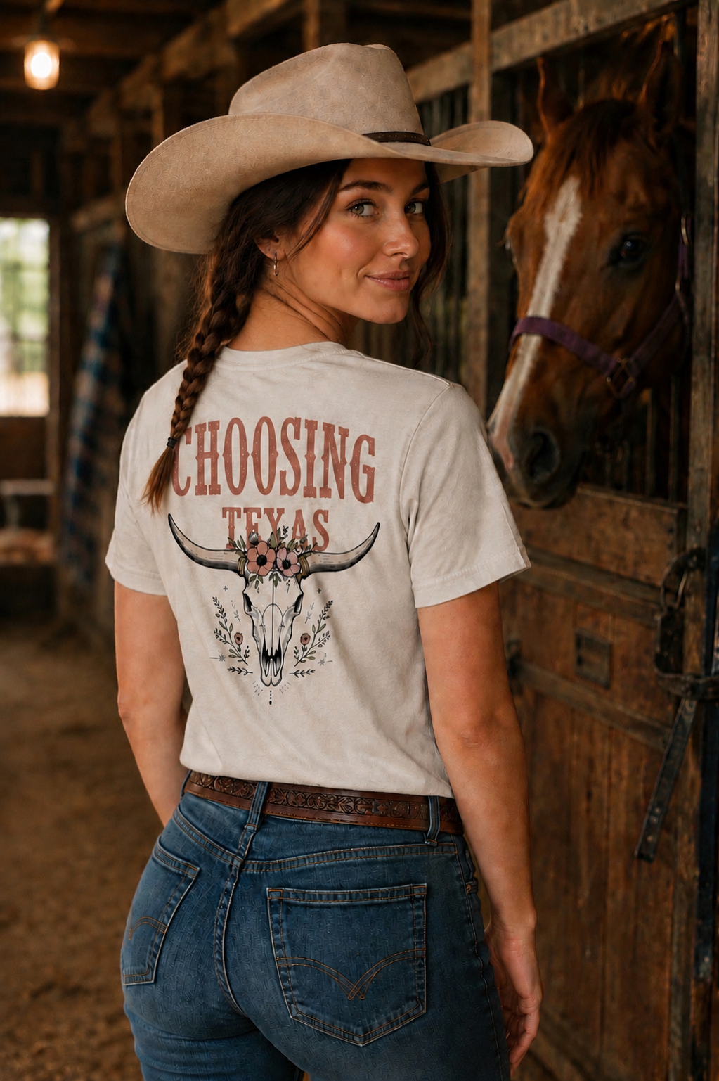 Woman wearing a t-shirt with 'Choosing Texas' design in a barn setting with a horse.